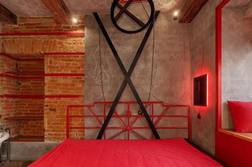 a red bed in a room with a brick wall at Masoch. Hotel & Cafe in Lviv