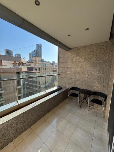 a balcony with a table and chairs and a large window at Ny Suites in Beirut