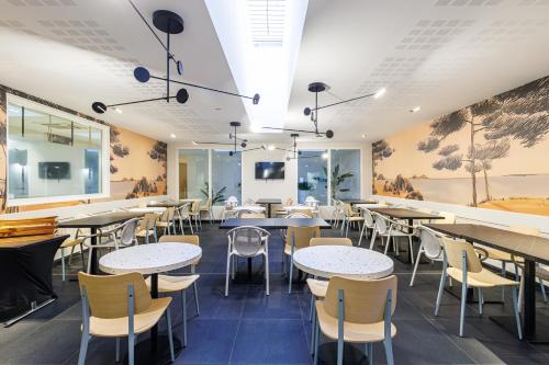 a restaurant with tables and chairs and paintings on the walls at Adagio Nice Centre in Nice