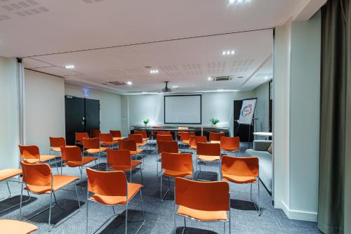 a conference room with orange chairs and a screen at Adagio Nice Centre in Nice