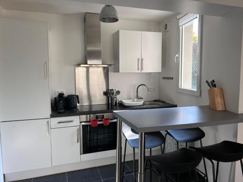 une cuisine avec des armoires blanches et une table et des chaises dans l'établissement L'Échappée belle - Séjour iodé près du parc, à Binic