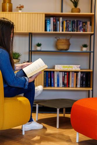 a girl sitting on a chair reading a book at Adagio Nice Centre in Nice