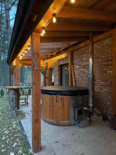 an outdoor patio with a large wooden deck with a fireplace at Ceglany Domek z jacuzzi, nad jeziorem, przy lesie in Tomaszkowo