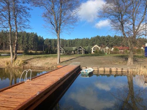 a dock on a lake with a boat in the water at Ceglany Domek z jacuzzi, nad jeziorem, przy lesie in Tomaszkowo