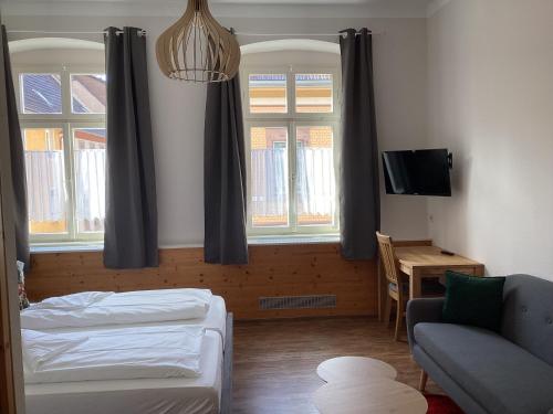 a bedroom with a bed and a couch and windows at Gasthaus zum Lamm in Ettenheim