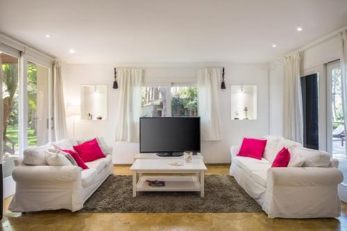 a living room with two white couches and a tv at El Oasis Villa Resort in La Eliana