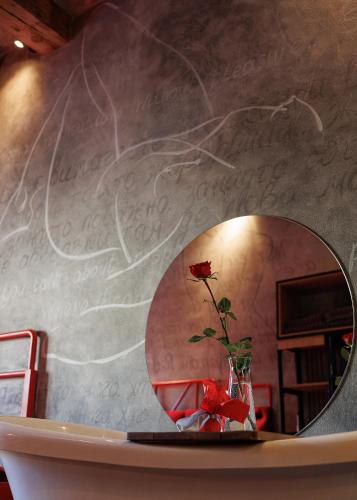 a mirror on a wall with a flower in a vase at Masoch. Hotel & Cafe in Lviv