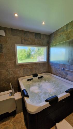 a large bath tub in a bathroom with a window at Maison calme avec Spa et beau paysage, à 40mn des plages in Saint-Jean-de-Livet