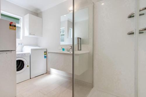 a bathroom with a shower and a washer and dryer at Wonderful Guest Suite Steps to St Heliers Beach in Auckland