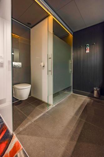 a bathroom with a toilet and a glass wall at Fletcher Hotel-Restaurant Teugel Uden-Veghel in Uden