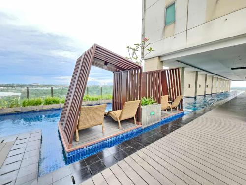 a deck with chairs and a swimming pool at Apartemen B Residence By LiviRooms BSD CITY in Cilandak