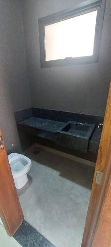 a bathroom with a toilet and a window at Casa Europa Barretos in Barretos