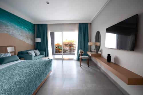 a bedroom with a bed and a tv and a couch at Amwaj Beach Club Abu Soma in Hurghada