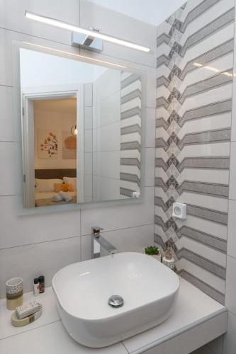 a white bathroom with a sink and a mirror at Sunny & Blue 2 in Parasporos