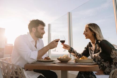 a man and woman sitting at a table with a glass of wine at Ethereal White Resort Hotel & Spa - Adults Only in Heraklio Town