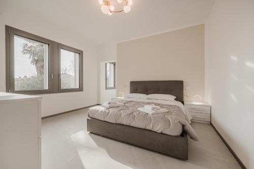 a white bedroom with a large bed and two windows at Dauli Suite - tra Venezia e Padova & Parcheggio in Dolo