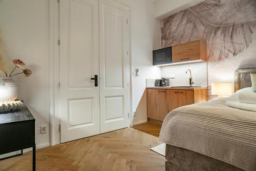 a white bedroom with a bed and a kitchen at Sting Old Town Ostrava in Ostrava
