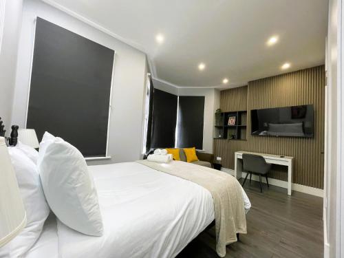 a bedroom with a large white bed and a desk at Luxury Guest House in Vibrant London Area in London