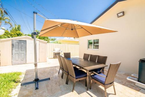 a wooden table with chairs and an umbrella at 4 BD 3BA Heated Pool Close to Beach in Boca Raton