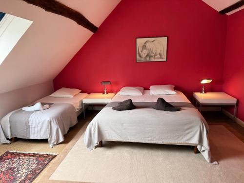- 2 lits dans une chambre aux murs rouges dans l'établissement Le Groupe des Huards au cœur du Val de Loire, à Cour-Cheverny