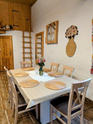 a dining room with a table with chairs and flowers at Piecówka Wysokie Kaczki in Kaczkowo