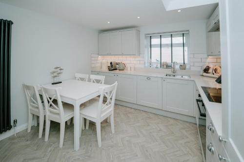 a white kitchen with a white table and chairs at First Light Hotel Lowestoft in Lowestoft