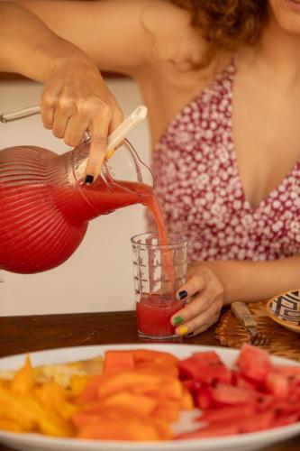 Een vrouw schenkt saus uit een theepot. bij Villa Continentes Brasil & Maison de rêve sur la plage in Guajiru