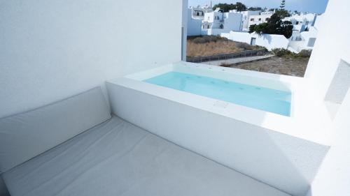 a bathtub in a white room with a window at Neo Suites in Fira