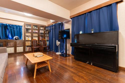 a living room with a piano and blue curtains at 天満橋 Guest House#有电梯 #步行大阪城 #赏樱花必打卡点 #直达梅田 京都 #免费wifi in Osaka