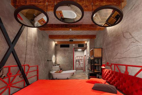 a bedroom with a red bed and a bathroom at Masoch. Hotel & Cafe in Lviv