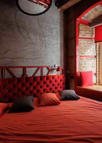 a red bed with two pillows in a bedroom at Masoch. Hotel & Cafe in Lviv
