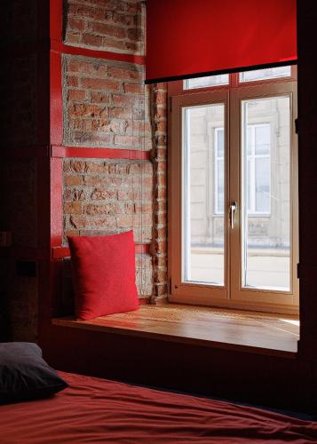 a window seat with a red pillow next to a brick wall at Masoch. Hotel & Cafe in Lviv