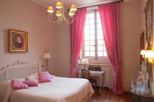a bedroom with a bed and a window with pink curtains at Château-Hôtel de Bourron in Bourron-Marlotte