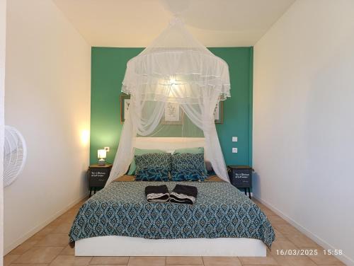 un dormitorio con una cama con dosel en La Perle Rose {3 ch. - 6 à 8 pers.}, en Sainte-Rose