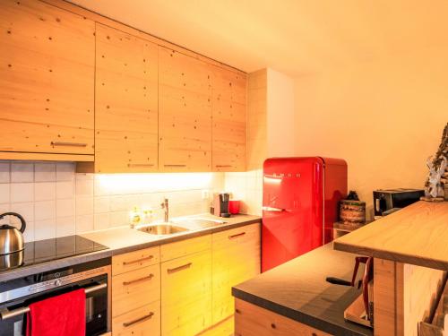 a kitchen with a red refrigerator and wooden cabinets at Apartment Le Hameau-21 by Interhome in Les Collons