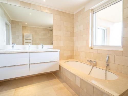 La salle de bains est pourvue de 2 lavabos, d'une baignoire et d'une fenêtre. dans l'établissement Villa Lei Suve by Interhome, à Grimaud