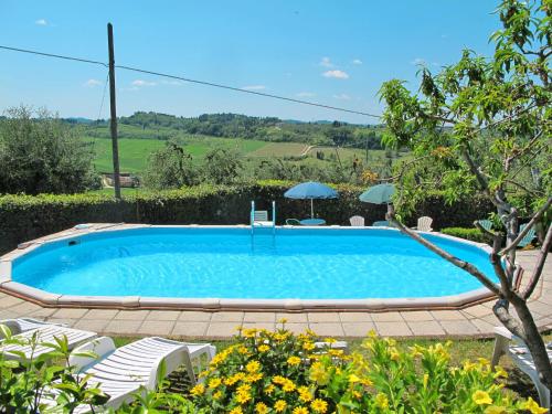 a swimming pool in a yard with chairs and an umbrella at Apartment L'Uccelliera-2 by Interhome in Canneto