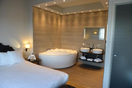 a bathroom with a tub and two sinks and a bed at Fletcher Hotel - Restaurant Nautisch Kwartier in Huizen