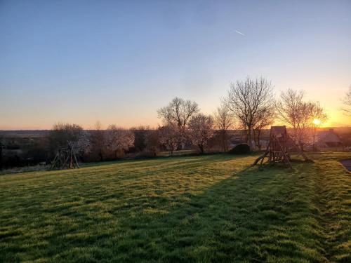 a field with trees and the sunset in the background at Le clos des sources in Isigny-sur-Mer