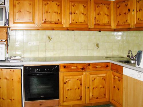 a kitchen with wooden cabinets and a black dishwasher at Apartment Garni Regina-2 by Interhome in Kappl