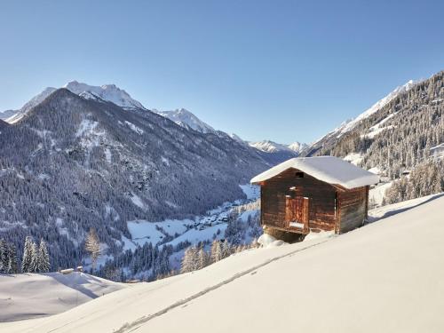 a cabin on a snow covered hill with mountains in the background at Apartment Garni Regina-2 by Interhome in Kappl