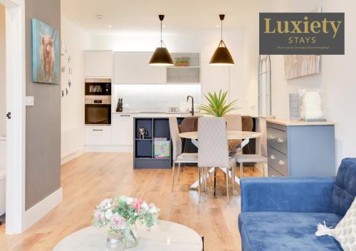 a living room with a blue couch and a kitchen at Gorgeous 1BR Apt - City Centre By Luxiety Stays in Southend-on-Sea