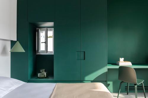 a bedroom with green walls and a bed and a chair at Neo Suites in Fira