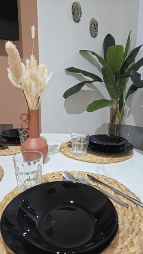 a black plate on a table with glasses and plants at Kasa in Centro INTERO APPARTAMENTO in Reggio Calabria