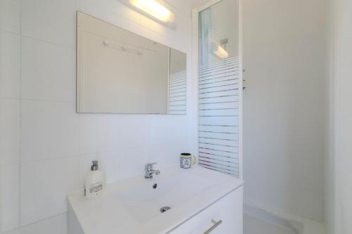 une salle de bain blanche avec un lavabo et un miroir dans l'établissement Petite maison avec jardin, à Royan