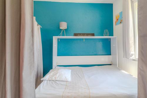 - une chambre bleue avec un lit blanc et un mur bleu dans l'établissement Petite maison avec jardin, à Royan
