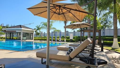 two lounge chairs with umbrellas next to a pool at Imperial Plaza Hotel, Juba in Juba