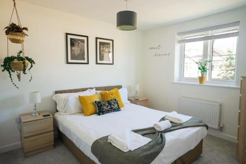 a bedroom with a bed with yellow pillows and a window at 2 Bedroom Apartment By Littlepiggyrentals Short Lets & Serviced Accommodation Peterborough With Fast Wi-Fi & Free Parking in Peterborough