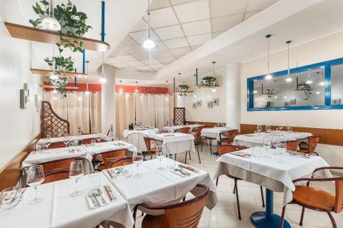 a dining room with white tables and chairs at Welcome Hotel in Legnano