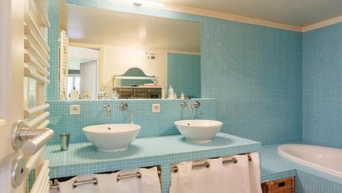 une salle de bain carrelée bleue avec deux lavabos et une baignoire dans l'établissement Le Jardin de Charenton à Paris, à Paris